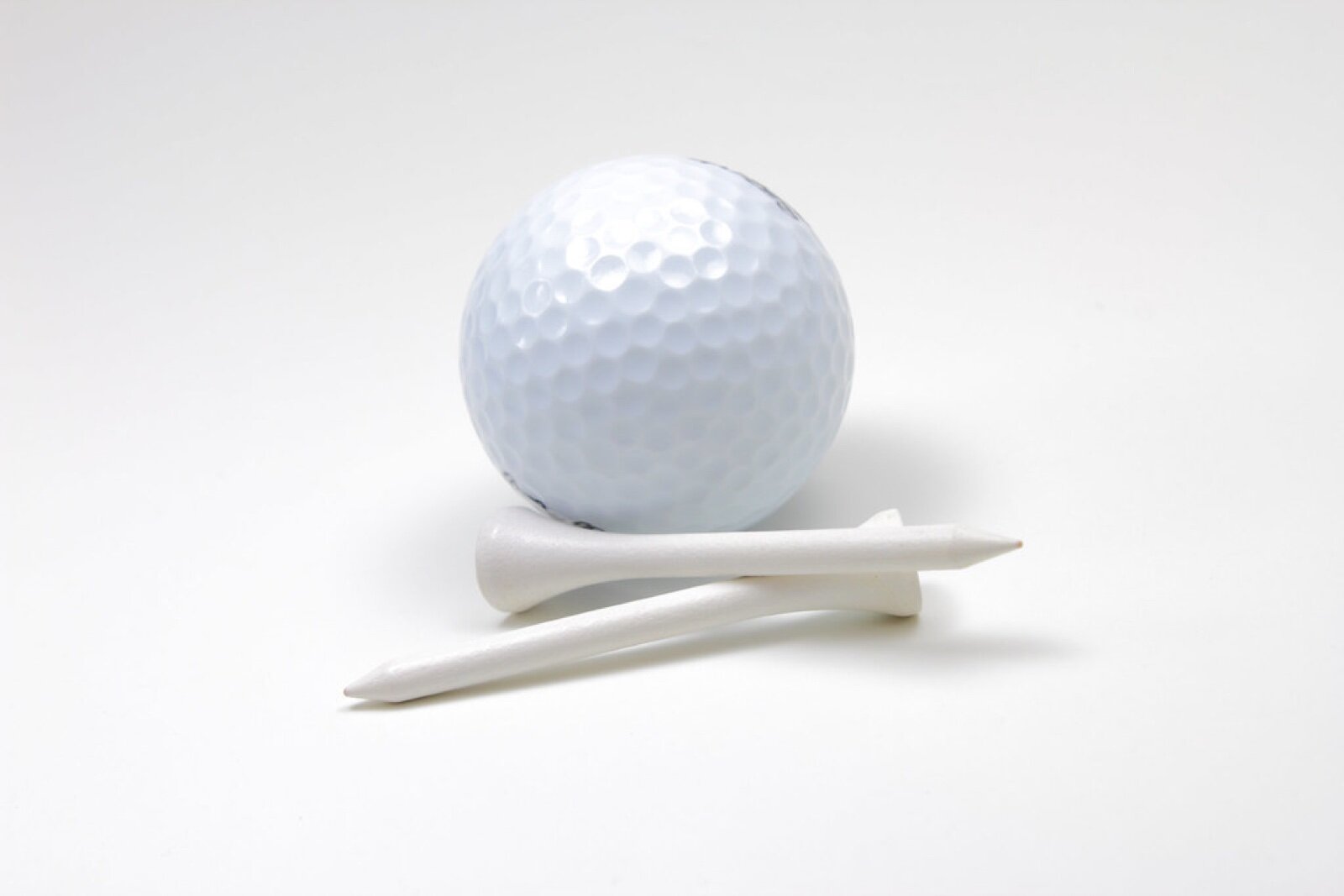 A white golf ball resting on two white wooden tees against a plain white background