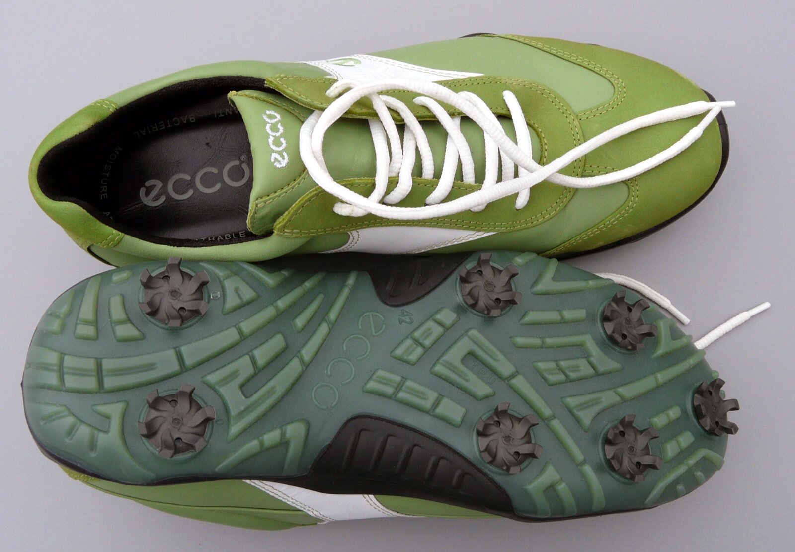 A pair of golf shoes photographed from above, one showing the upper and one showing the sole with replaceable soft spikes
