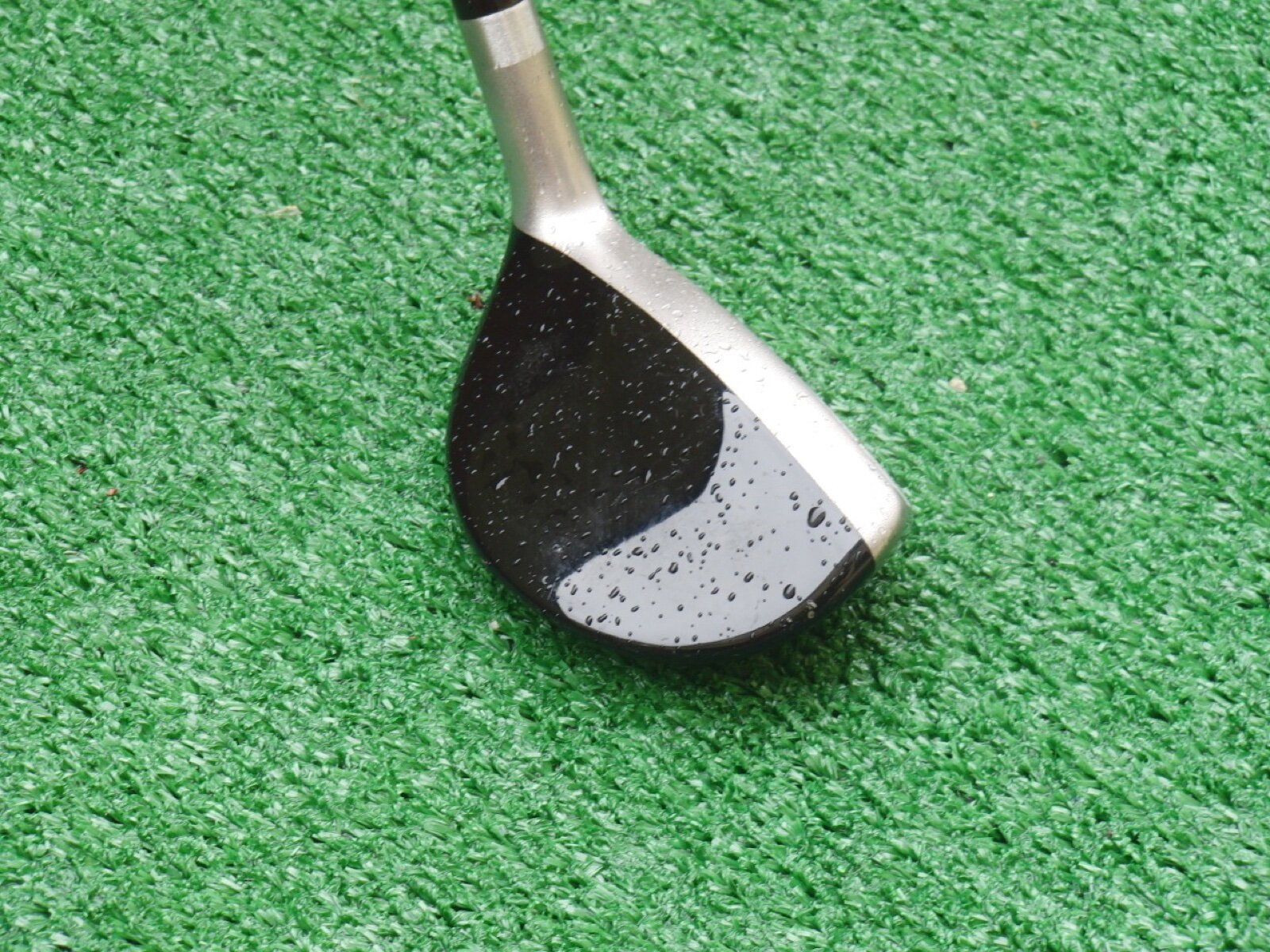 The head of a Ping G10 24 degree hybrid golf club resting on a practice mat