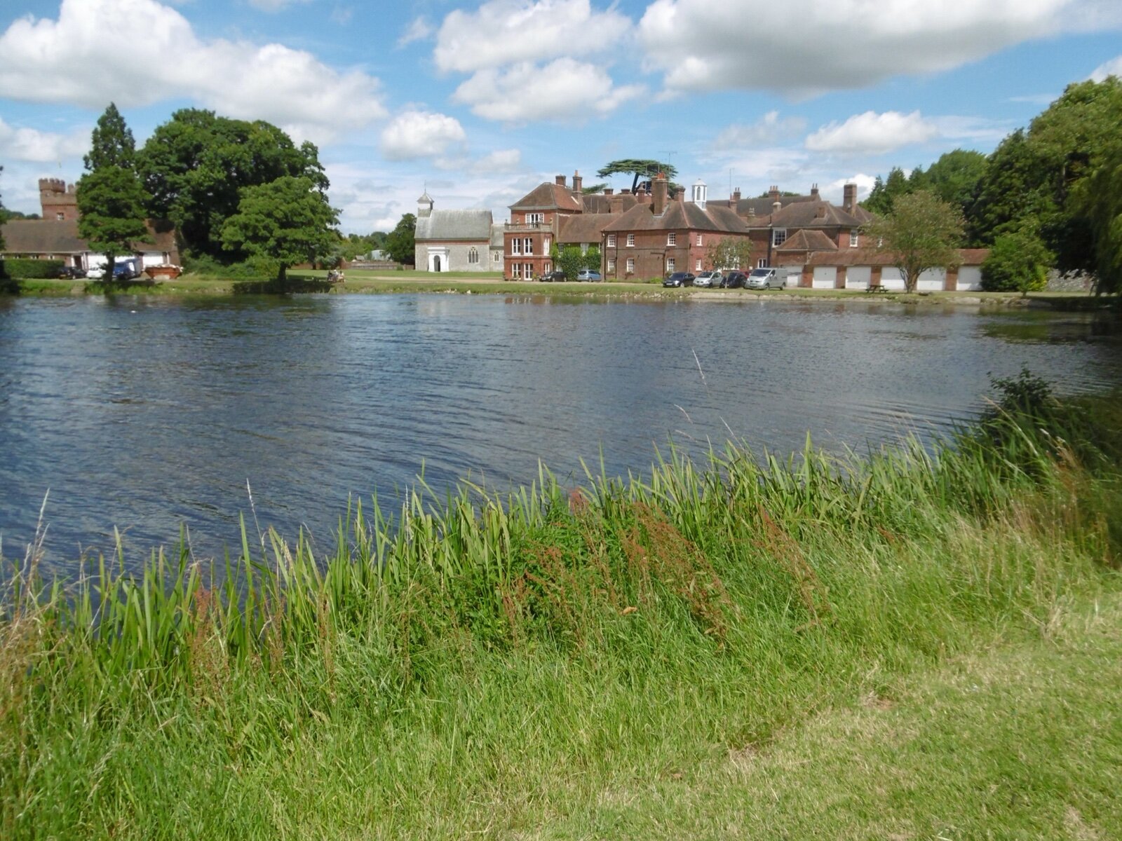 Lullingstone Castle seen across its lake, with the Tudor gatehouse tower and the church of St Botolph among the trees